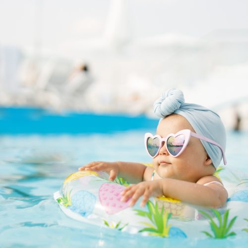 Cute,Funny,Toddler,Girl,In,Colorful,Swimsuit,And,Sunglasses,Relaxing Cute funny toddler girl in colorful swimsuit and sunglasses relaxing on inflatable toy ring floating in pool have fun during summer vacation in tropical resort. Child having fun in swimming pool.